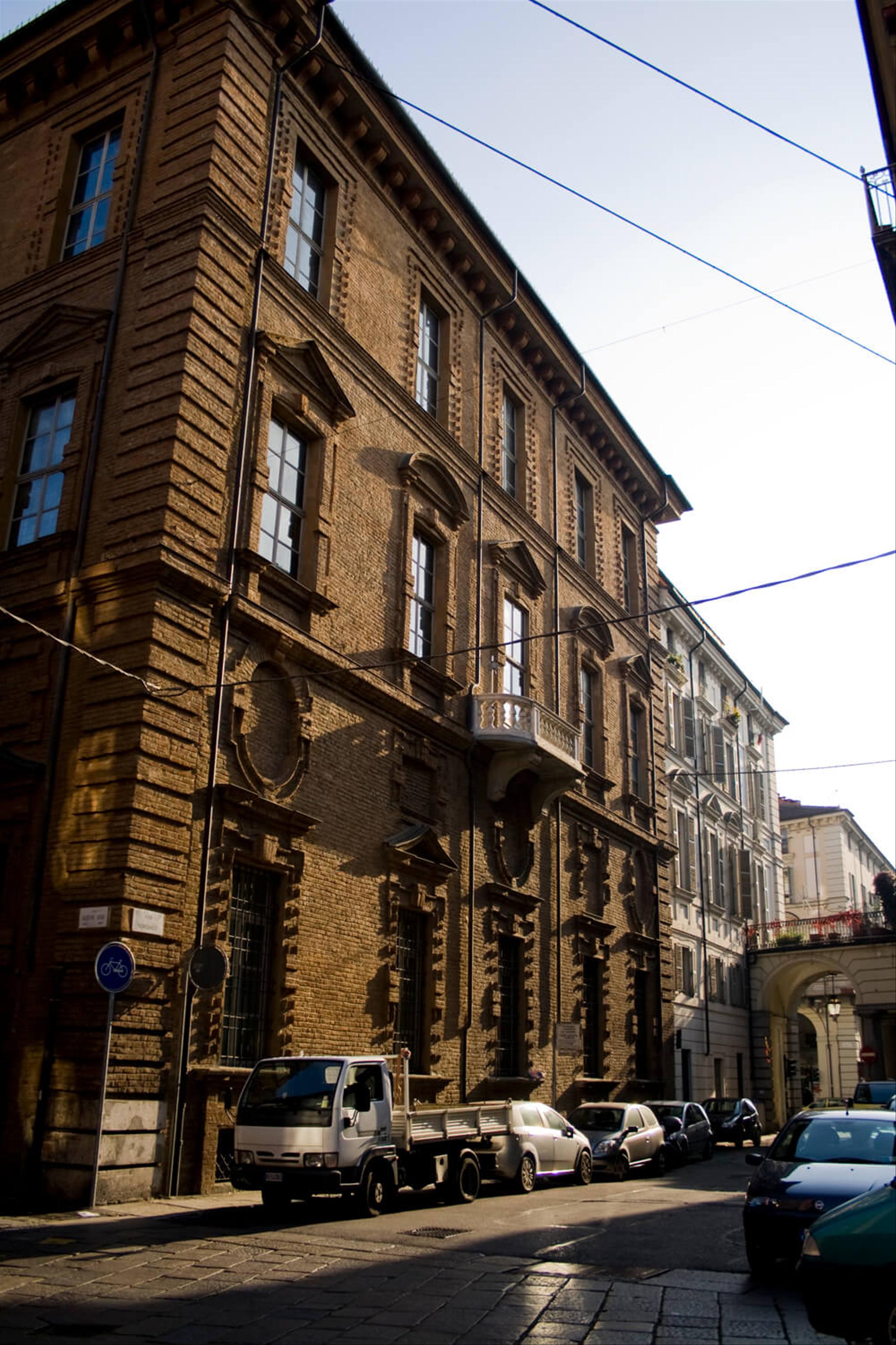 A city building with a few parked cars in front on the side of the road